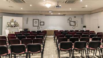 Un salón de conferencias con filas de sillas, un atril y un proyector.