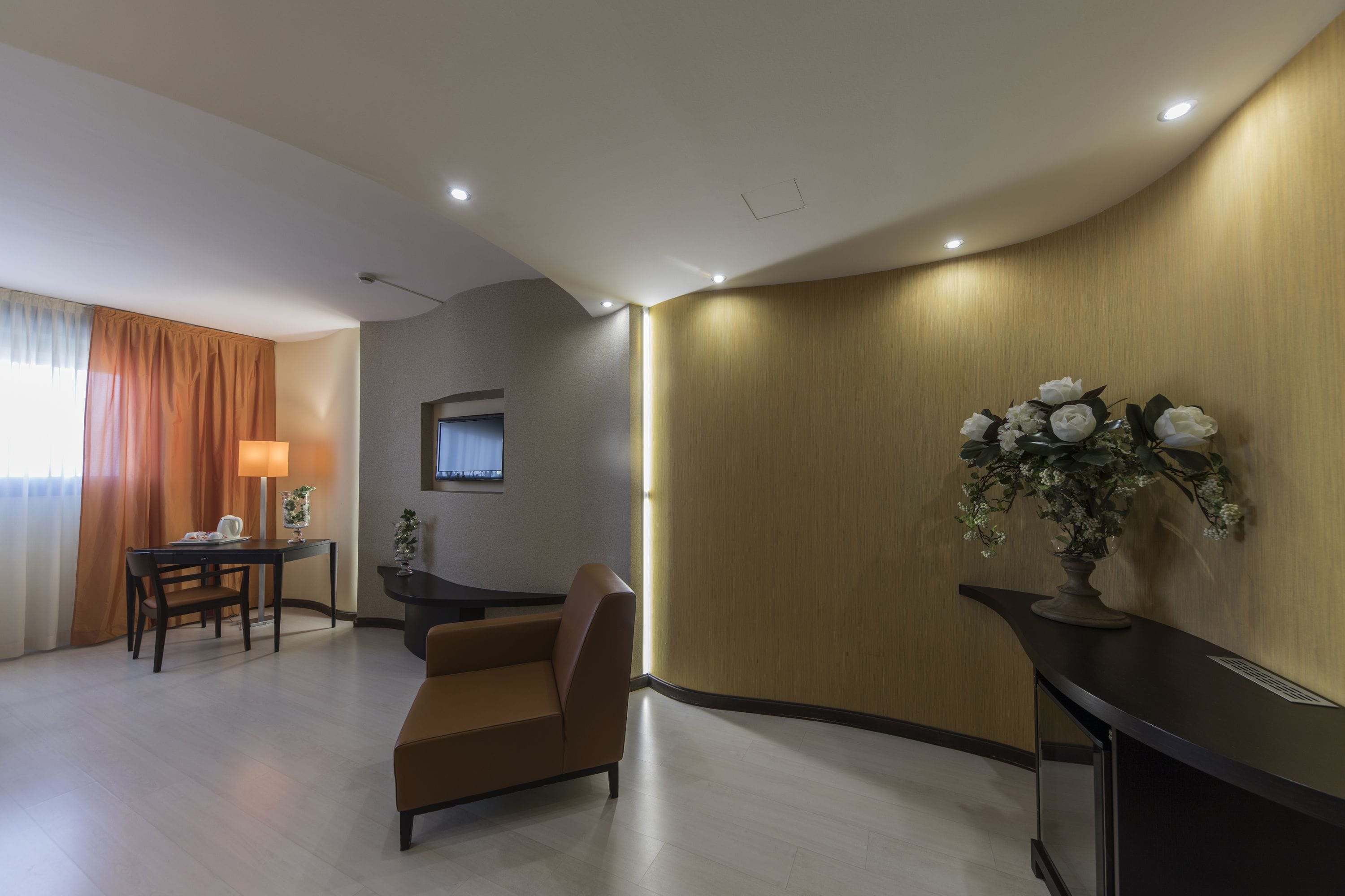 Une chambre d’hôtel moderne, équipée d’un canapé, d’un bureau et d’une plante décorative.