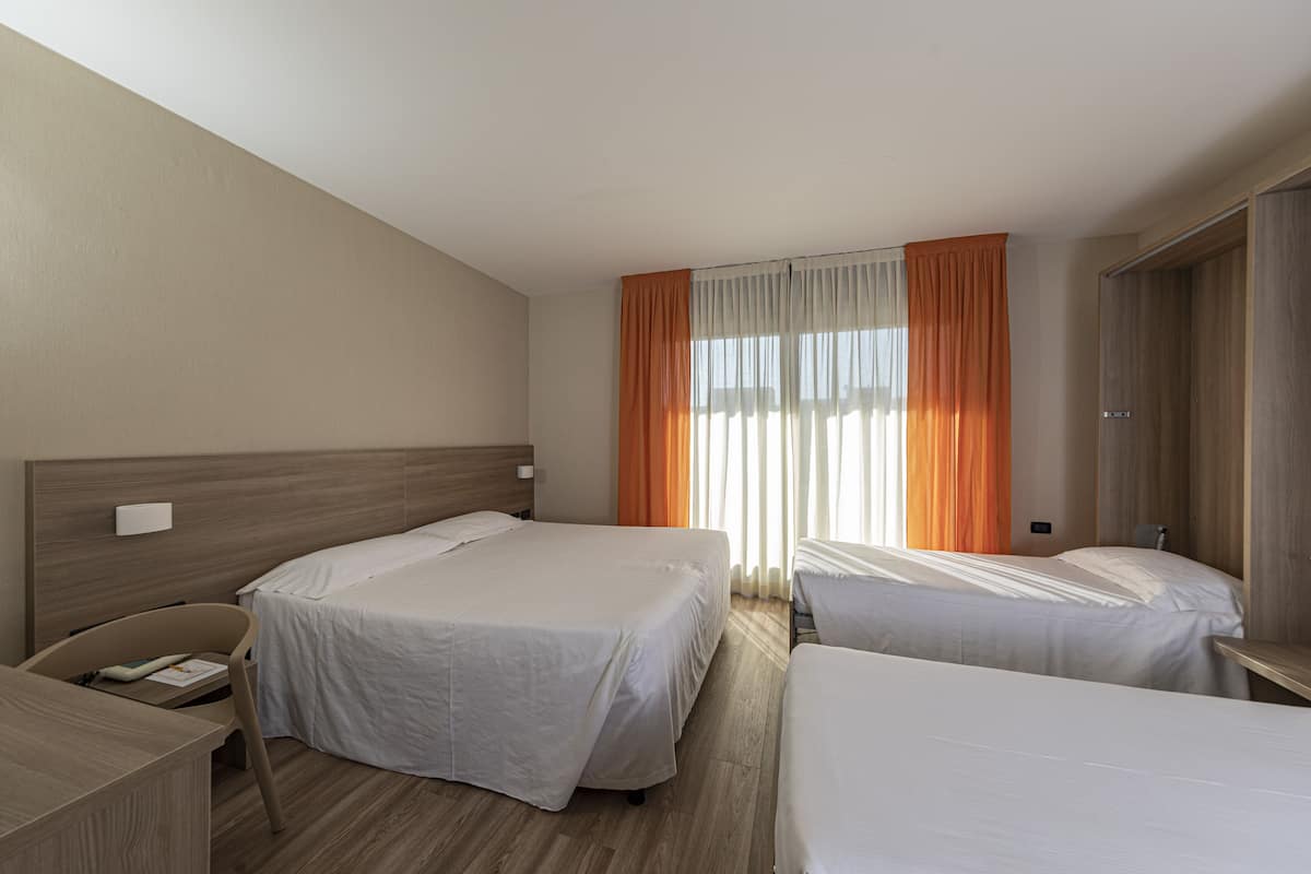 A hotel room with two beds, a desk, and a wardrobe.