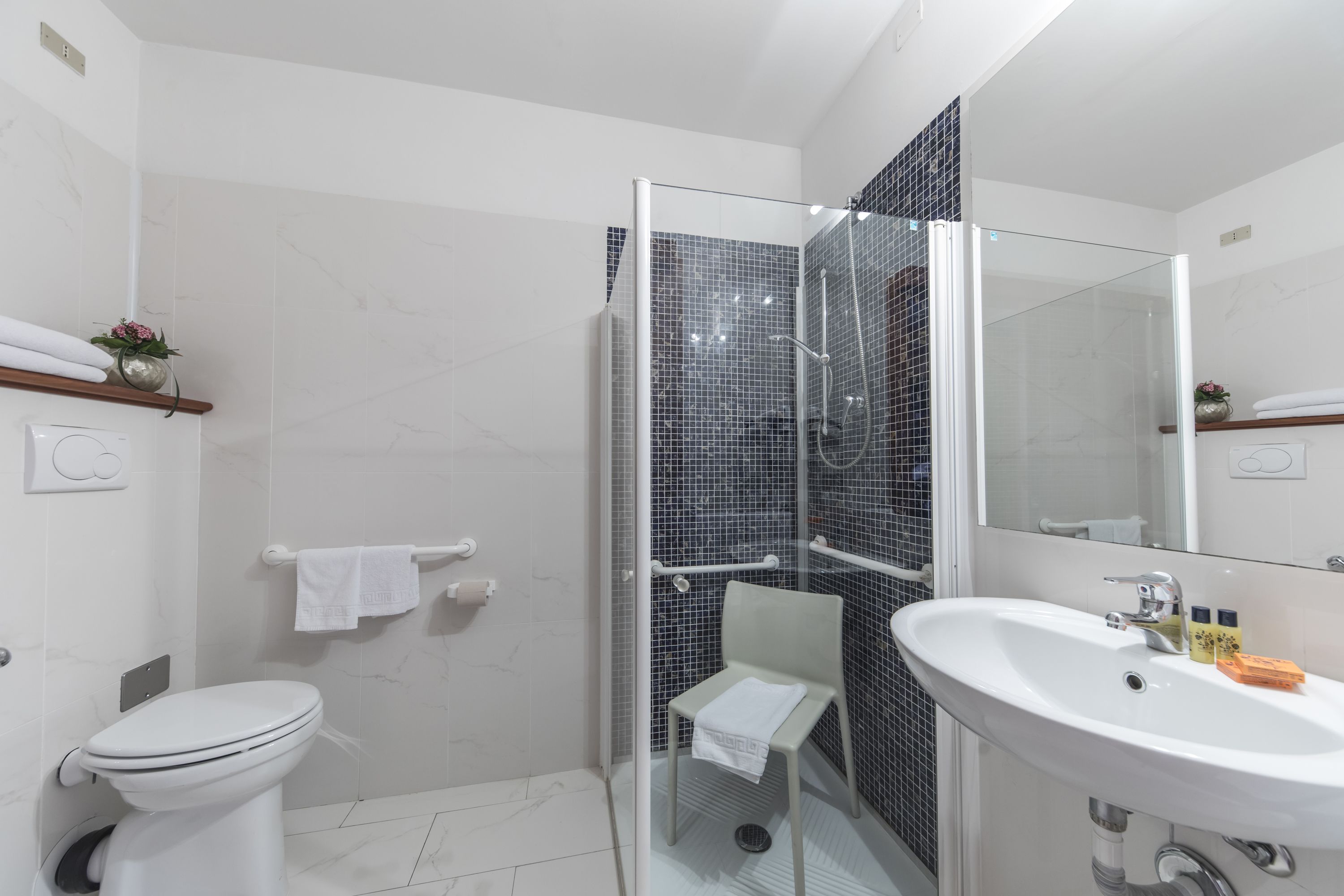 Een moderne badkamer met een douchecabine van glas, een wit wastafelmeubel en een toilet.