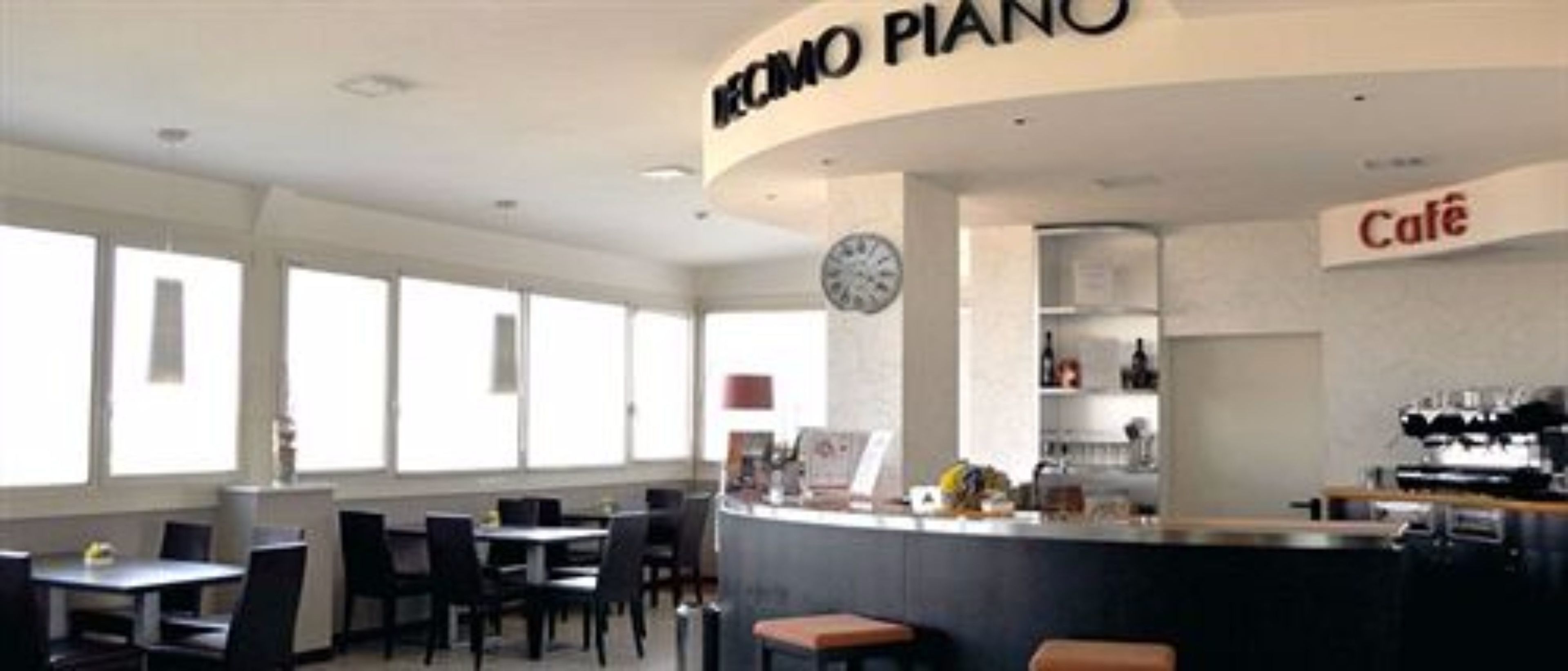 Un caffè moderno con un pianoforte, tavoli e sedie.