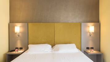 Una habitación de hotel con una cama grande, dos mesitas de noche y lámparas de pared.