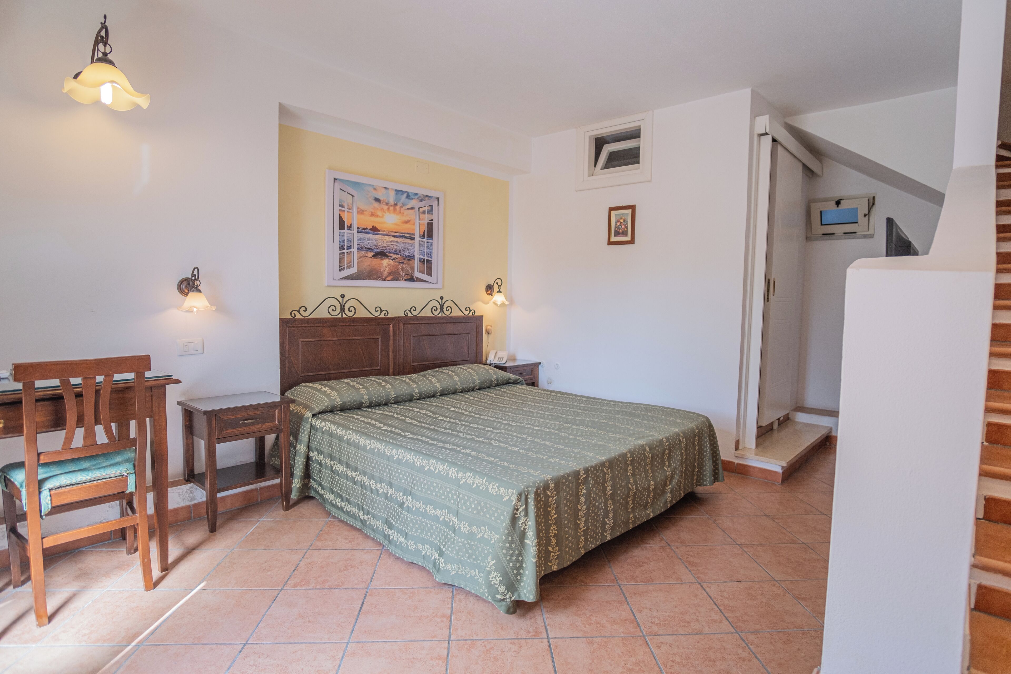 Un dormitorio con cama, escritorio, silla y un cuadro en la pared.