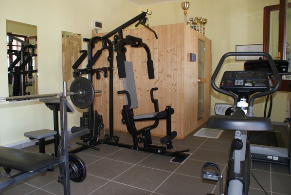 A gym with weightlifting equipment, a bench, and a stationary bike.