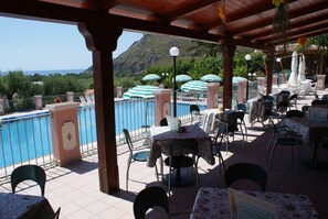 An outdoor patio with tables and chairs, a pool, and a view of the sea. - Hotel Ristorante Borgo La Tana (Maratea)