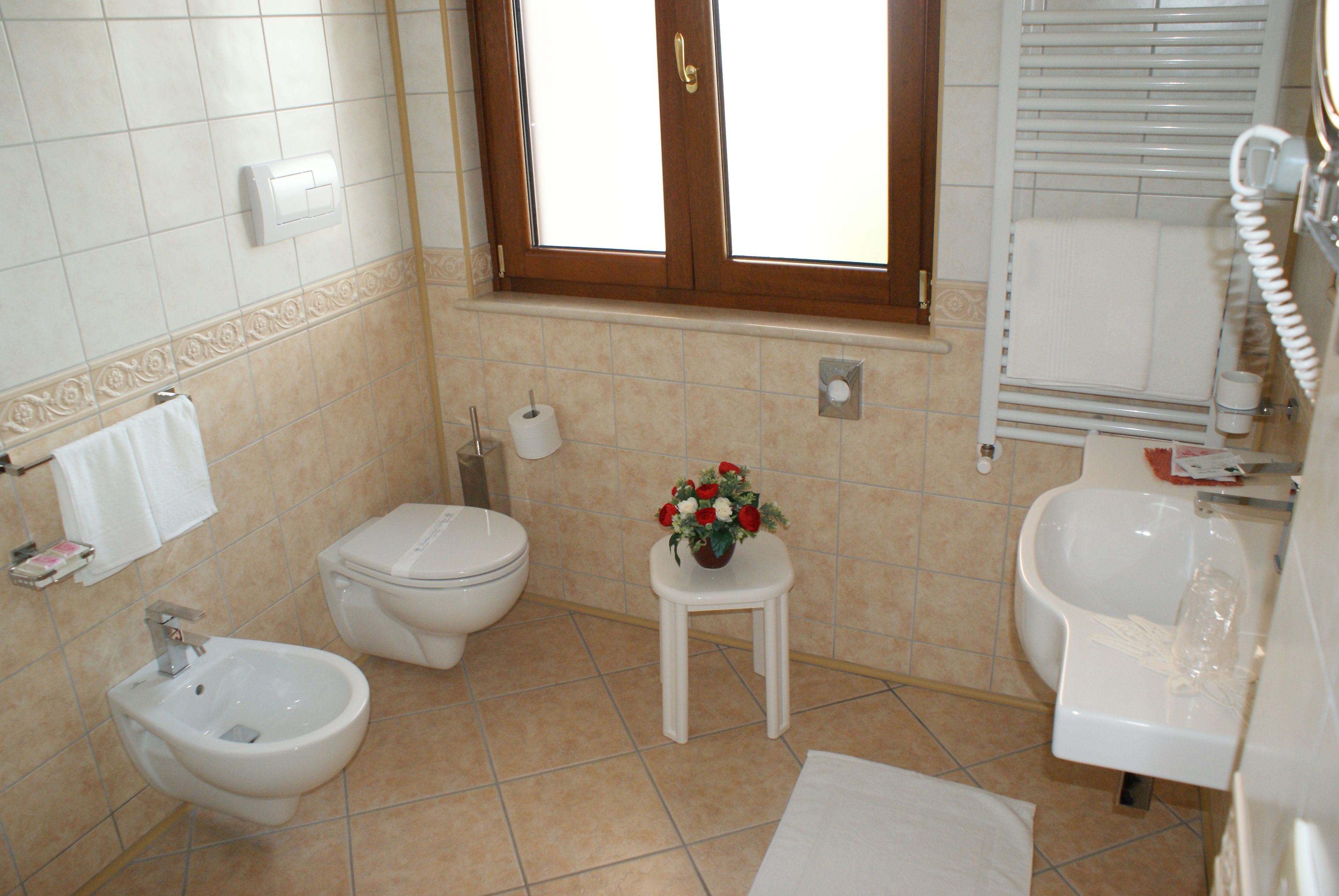 Et badeværelse med bidét, toilet og håndvask.