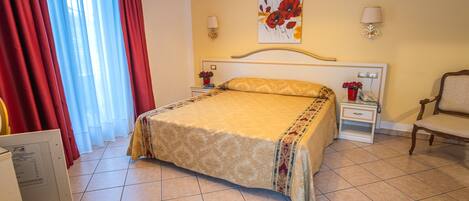 A hotel room with a large bed, two bedside tables, a chair, a wall-mounted lamp, and a painting.