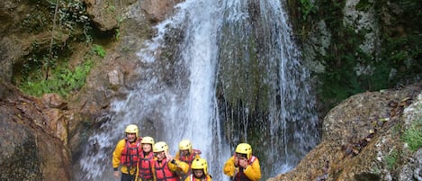 Un grupo de personas con chalecos amarillos y cascos de pie junto a una cascada.