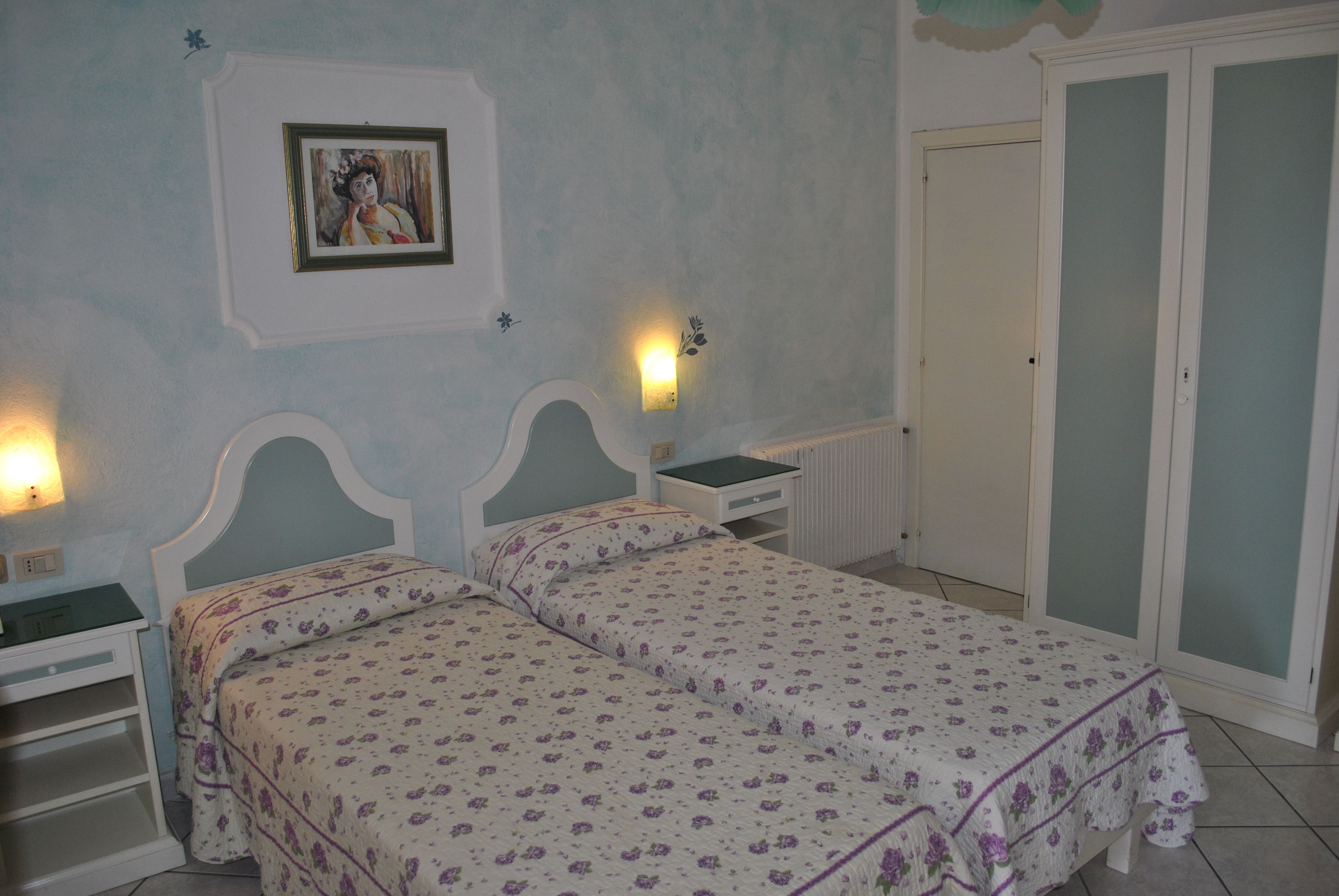 A bedroom with two beds, a nightstand, a dresser, and a wardrobe.