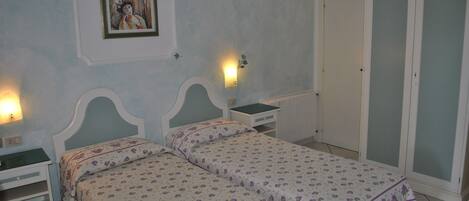 A bedroom with two beds, a nightstand, a dresser, and a wardrobe.