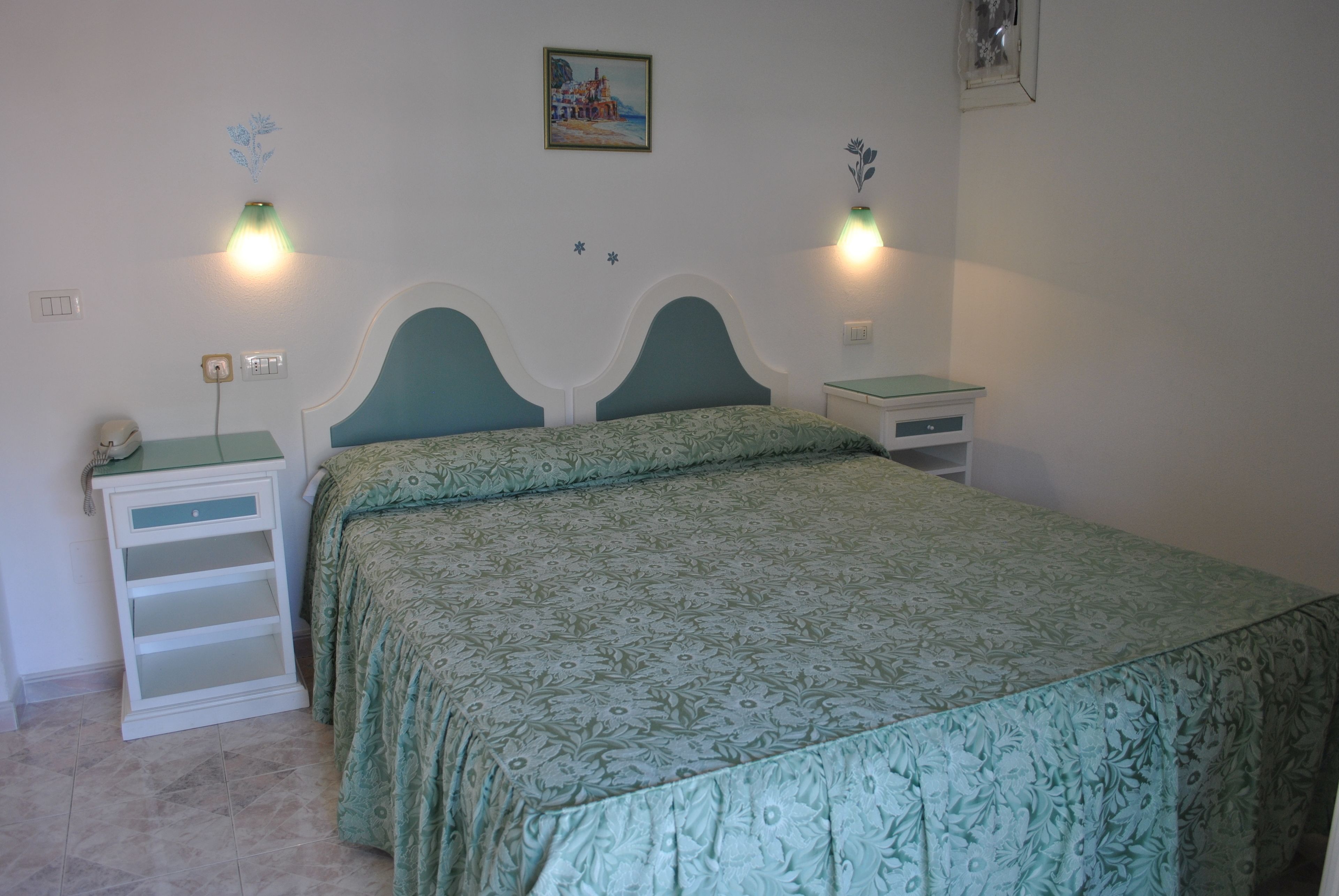 A bedroom with a bed, nightstands, and a wall-mounted lamp.