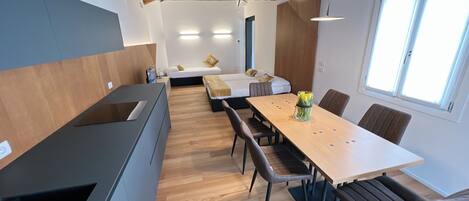 Una cocina moderna con estufa integrada, piso de madera y comedor con mesa y sillas.
