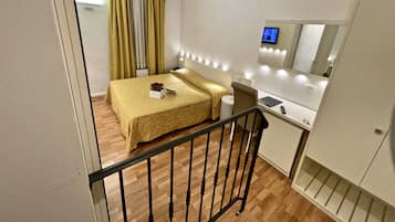 Una habitación de hotel con cama, mesita de noche y un escritorio pequeño con silla.
