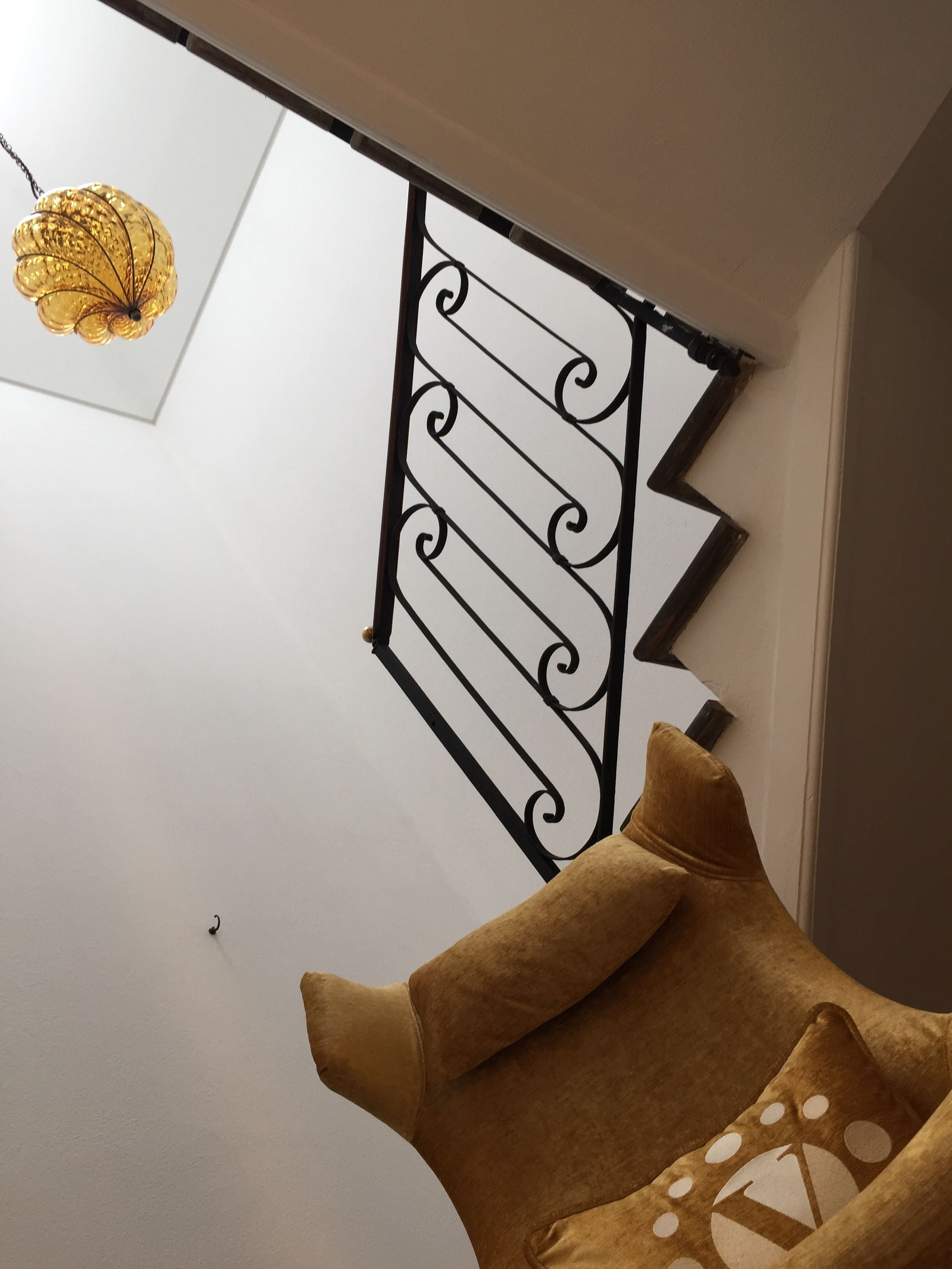 A room with a white wall, a black decorative metal piece, and a brown chair with a patterned cushion.
