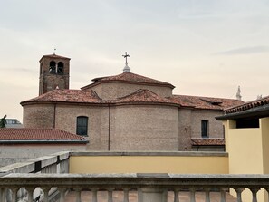 Un edificio histórico con una torre de campanas y una cúpula, que presenta fachada de ladrillo y una pared amarilla en primer plano.