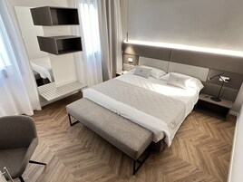 A modern bedroom with a large bed, bedside tables, a bench, and built-in shelving.