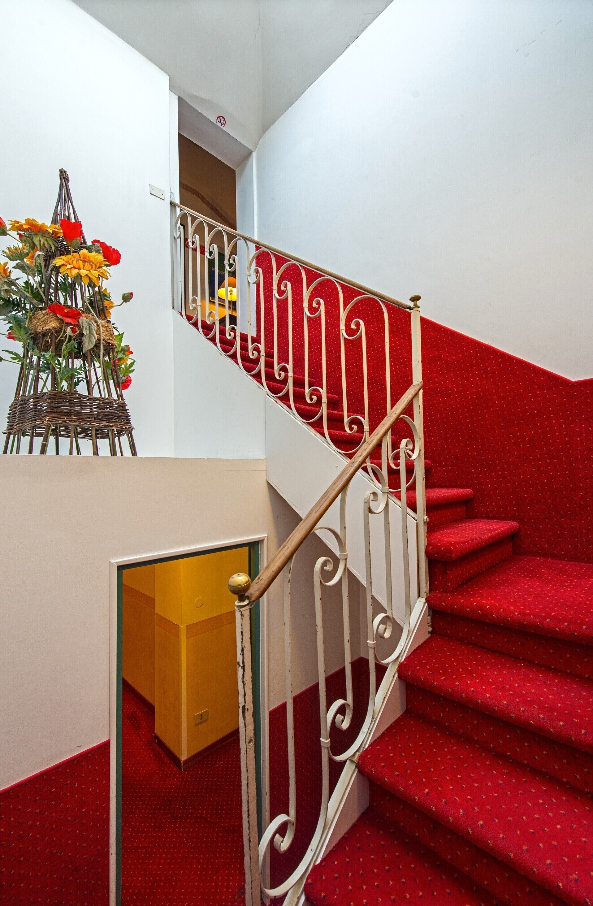 A staircase with red carpeted steps and white metal railings.