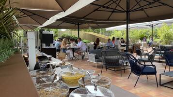 An outdoor patio area with tables and chairs, a buffet with food containers, and a television screen.