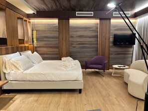 Relax in a stylish room with a large bed, flat-screen TV, and comfortable armchair.