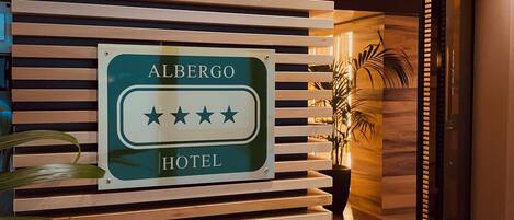 A hotel sign with a four-star rating, wooden slats, and a potted plant.