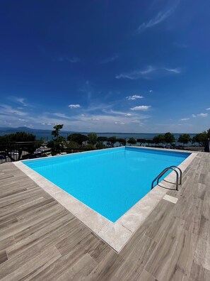 A rectangular swimming pool with a clear blue water surface, surrounded by a wooden deck. - Alevic Hotel Sirmione (Sirmione)