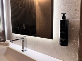 Un bagno dal design moderno, con uno specchio grande, un dispenser per sapone nero e un rubinetto cromato.