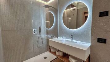 Un bagno moderno con uno specchio grande, una doccia e un mobile lavabo.
