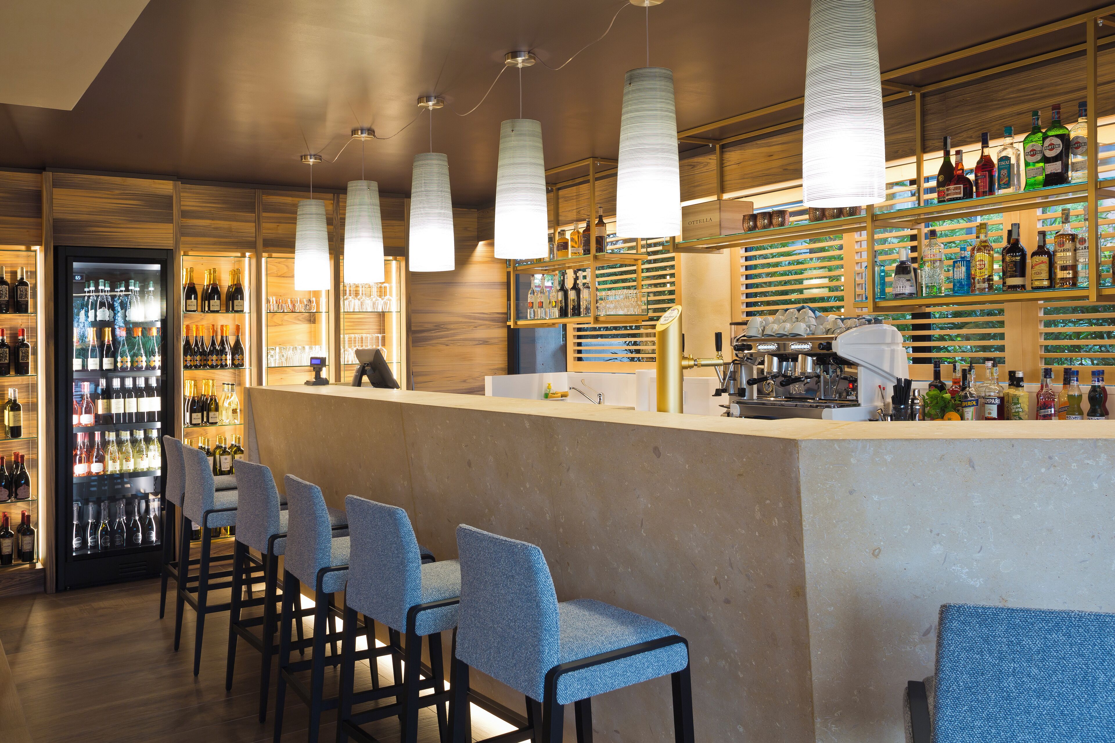 A bar area with a counter, bar stools, and shelves stocked with bottles.