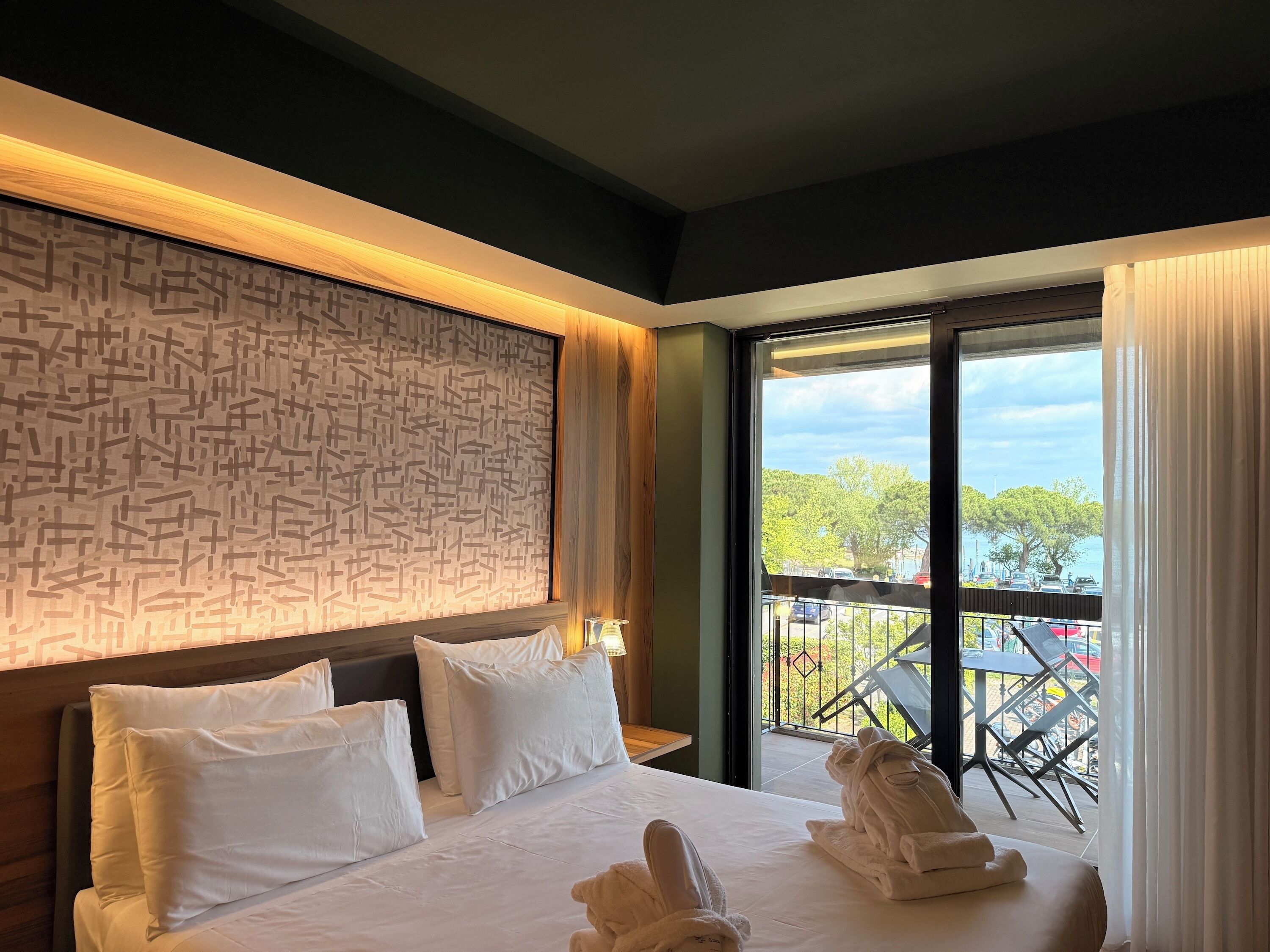 Habitación de hotel con una cama grande, pared con diseño y balcón con vistas.