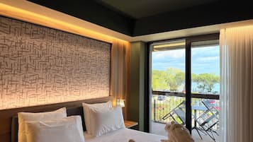 Habitación de hotel con una cama grande, pared con diseño y balcón con vistas.