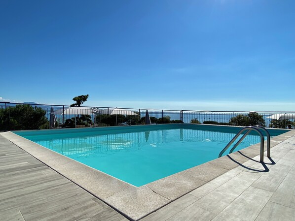 Enjoy a refreshing swim in the pool surrounded by a deck area and a scenic view.