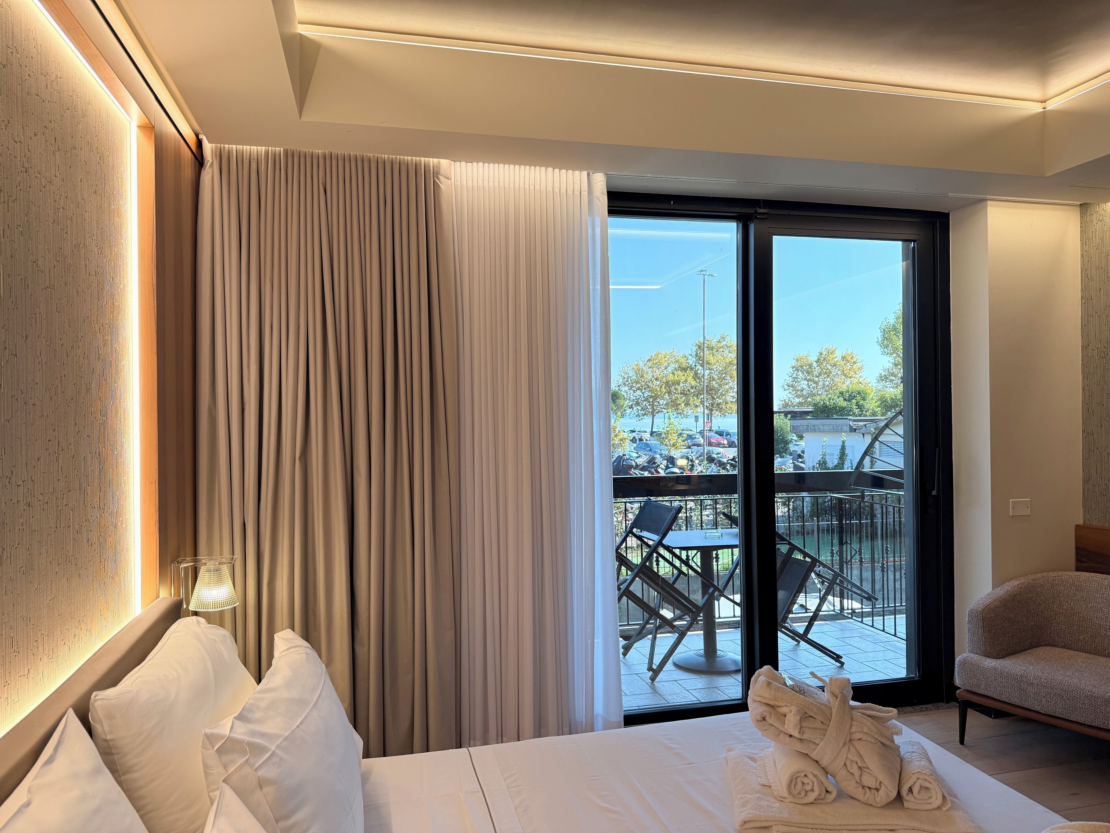 Habitación de hotel con cama, una silla, una mesa y un balcón con vistas al exterior.