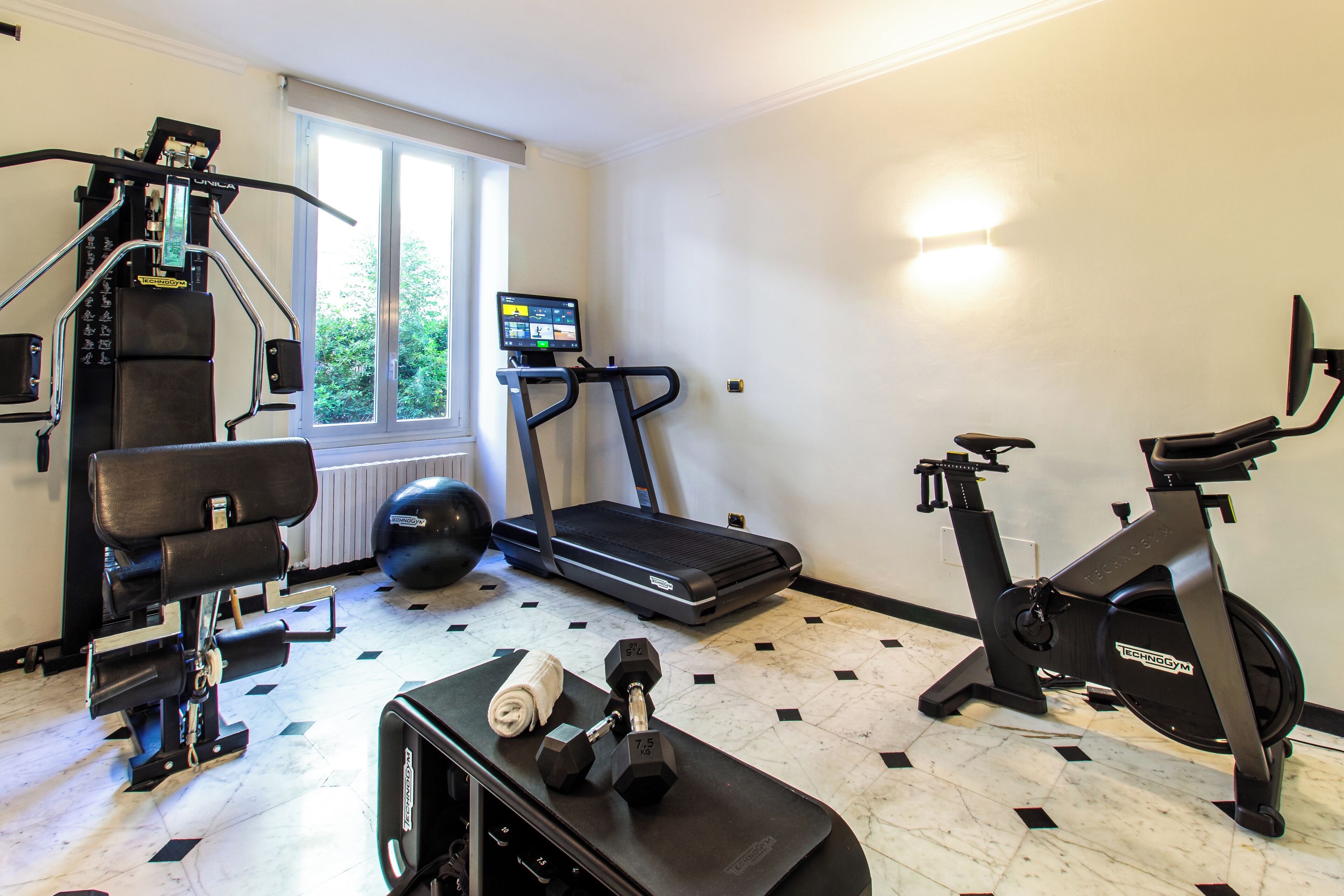 Une salle de sport à domicile équipée de matériel d’exercice, notamment un tapis de course, un vélo elliptique et des poids.