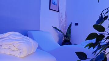 Una habitación moderna con un sofá blanco, una mesita y una planta en maceta.