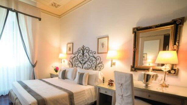 A hotel room with a bed, bedside tables, a desk, a chair, a mirror, and a window with curtains. - Hotel Jolanda (Santa Margherita Ligure)