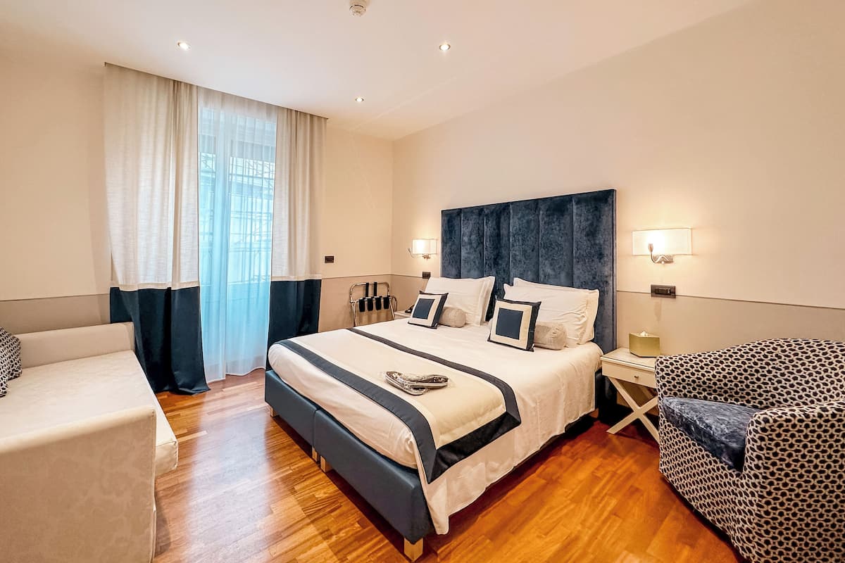 Une chambre d’hôtel moderne avec un grand lit, une table de chevet, une chaise et une fenêtre avec des rideaux.