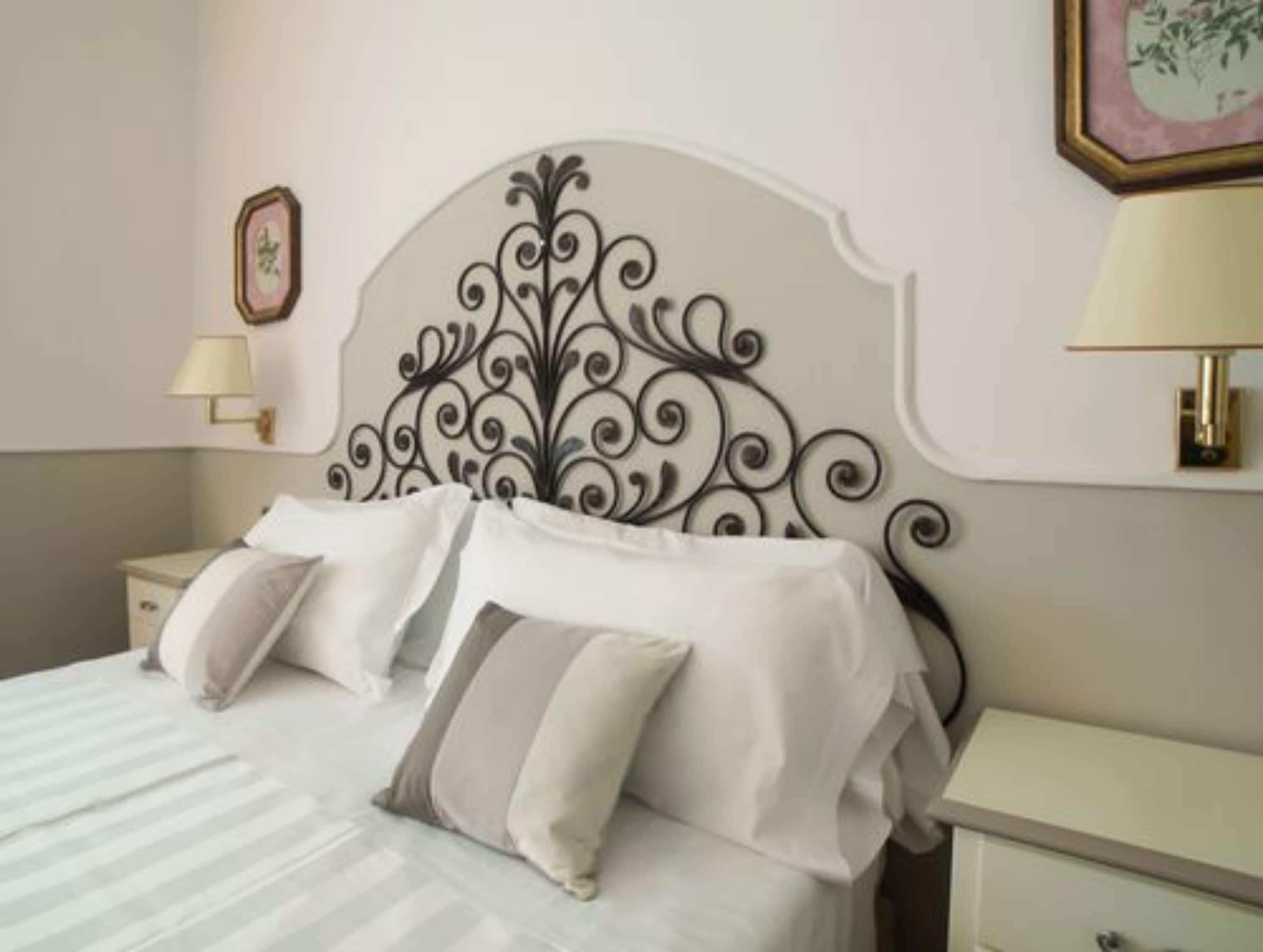 A neatly made bed with a decorative headboard, bedside tables, and wall-mounted lamps.