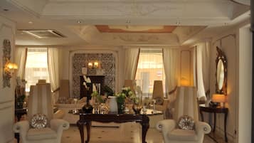Een weelderige woonkamer met een hoge plafond, sierlijke lijsten en klassiek meubilair.