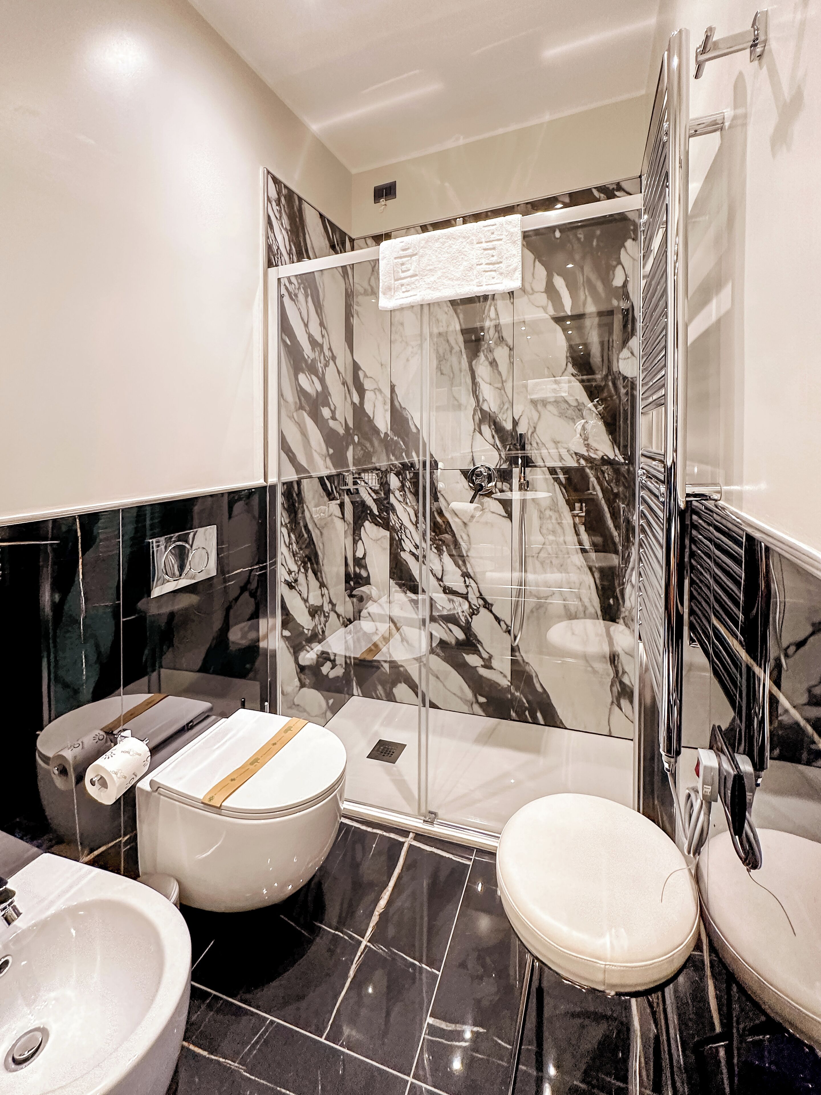 A modern bathroom with a glass shower enclosure, a toilet, a bidet, and a sink.
