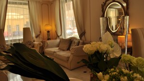 A well-lit living room with a sofa, a large mirror, and a vase of flowers. - Hotel Jolanda (Santa Margherita Ligure)