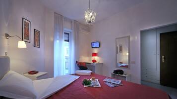A hotel room with a bed, bedside table, lamp, TV, and a door.