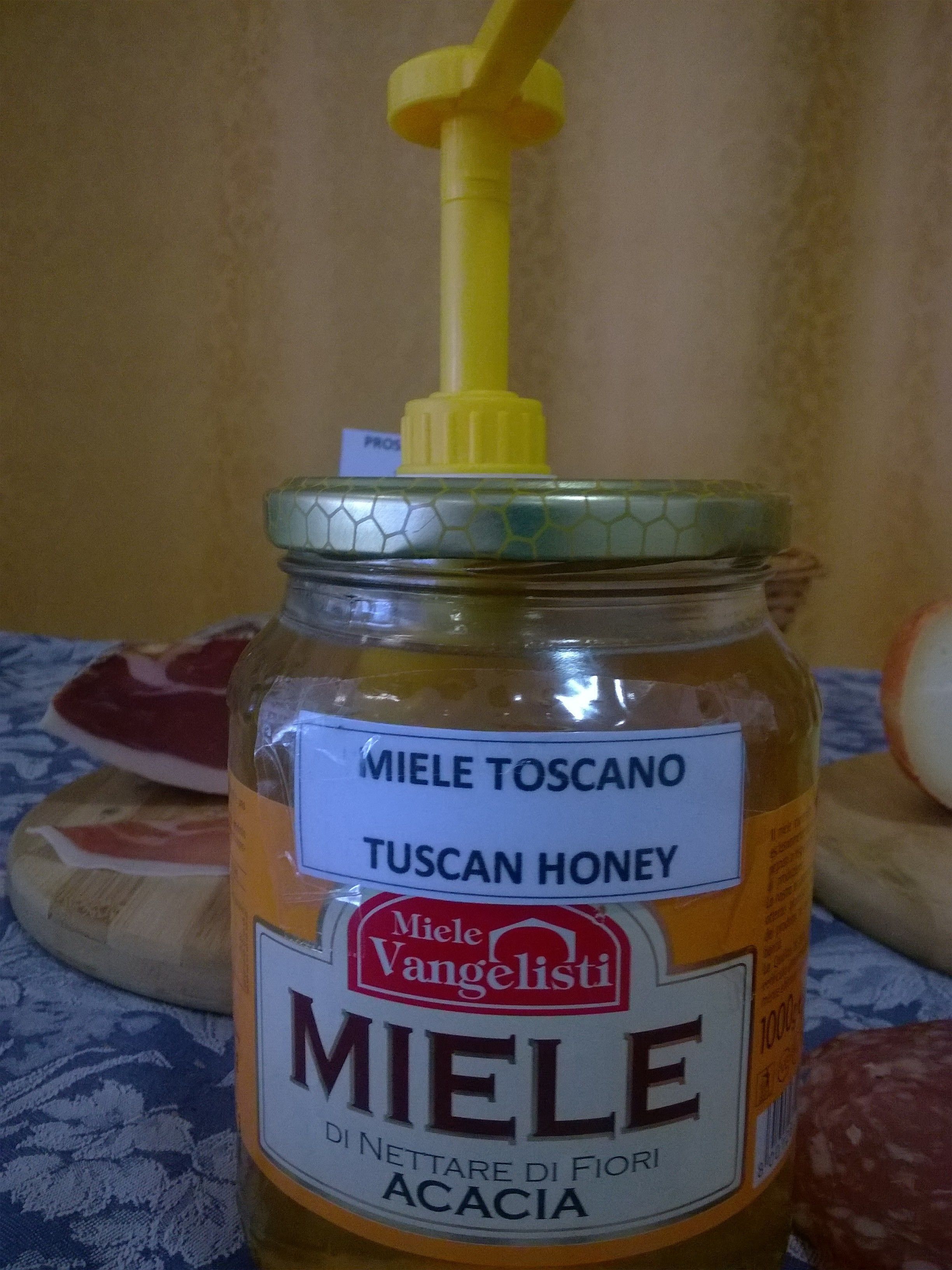 Un vasetto di miele toscano con un erogatore giallo.
