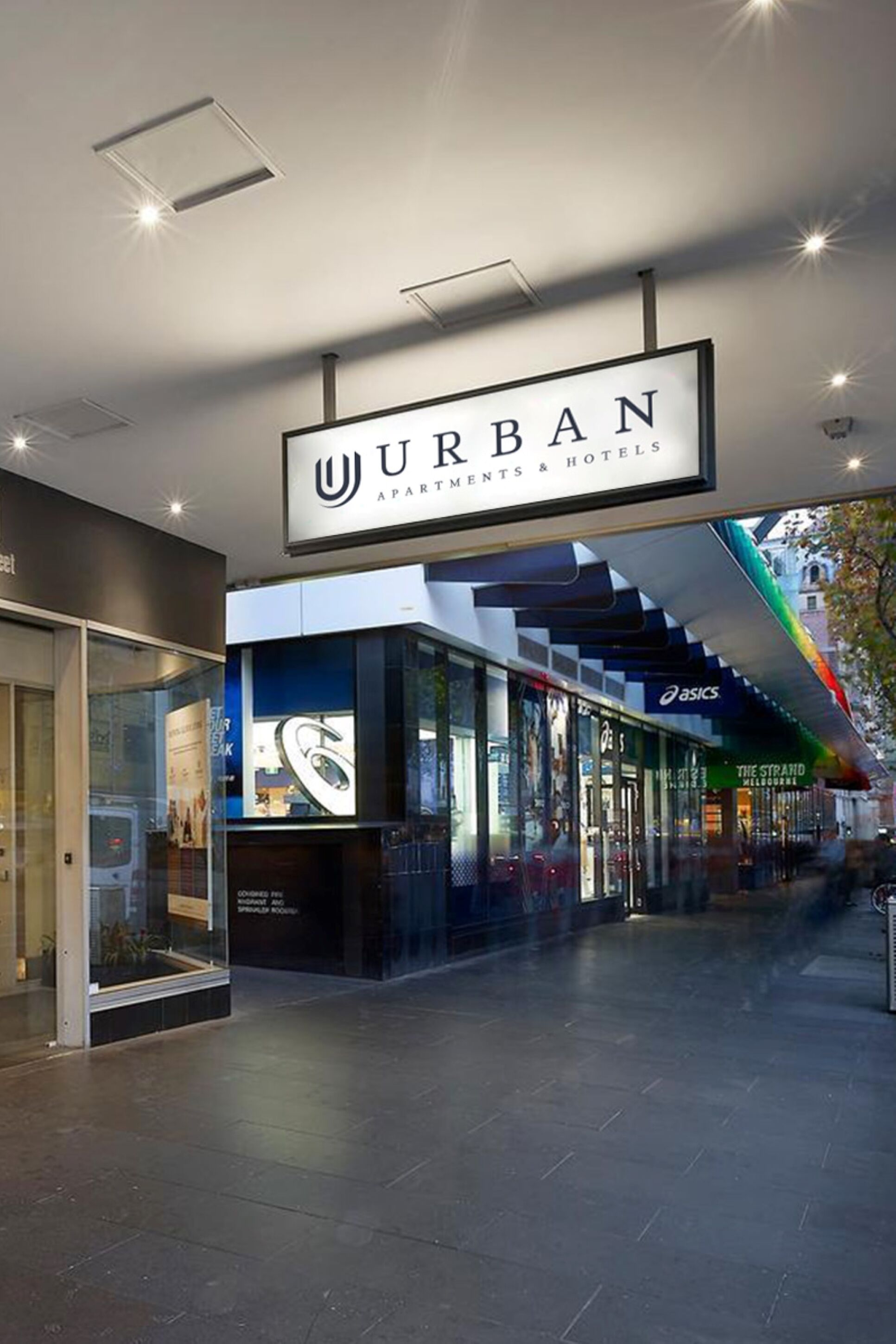 A modern hotel entrance with a prominent sign for 'URBAN APARTMENTS & HOTELS'.