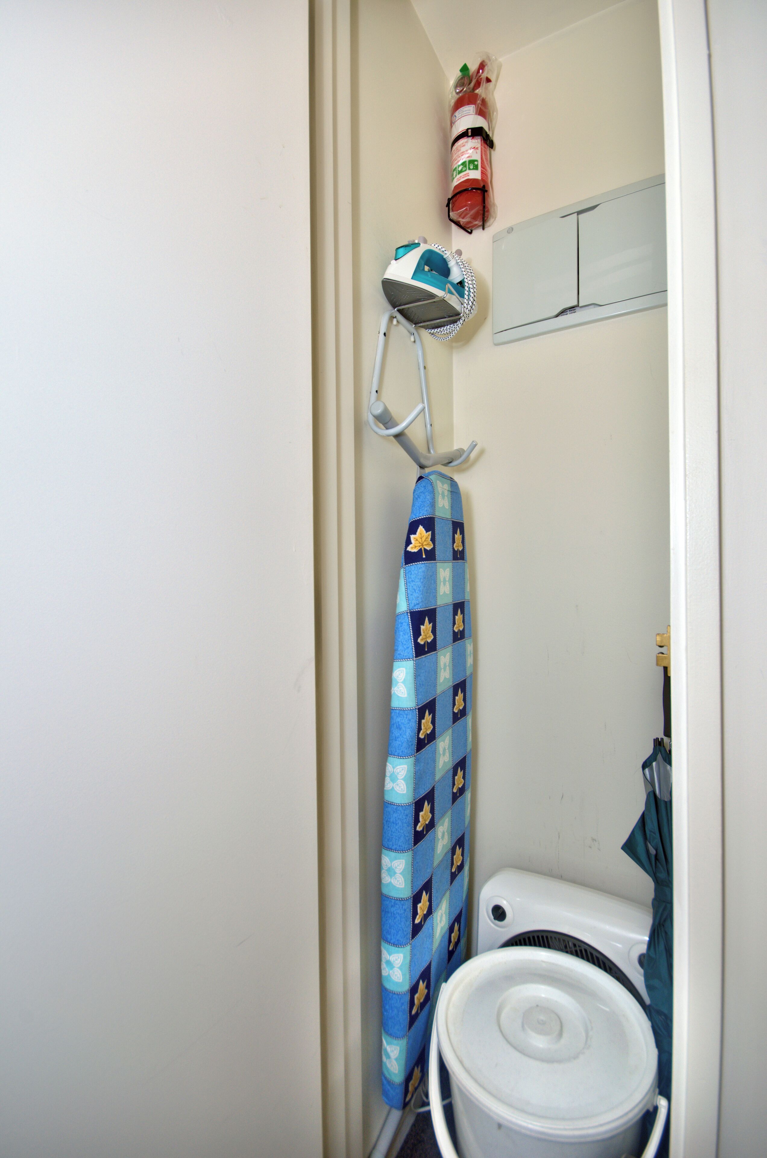 Een badkamer met een wit toilet, een blauw douchegordijn en een witte emmer.