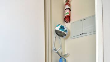 Een badkamer met een wit toilet, een blauw douchegordijn en een witte emmer.