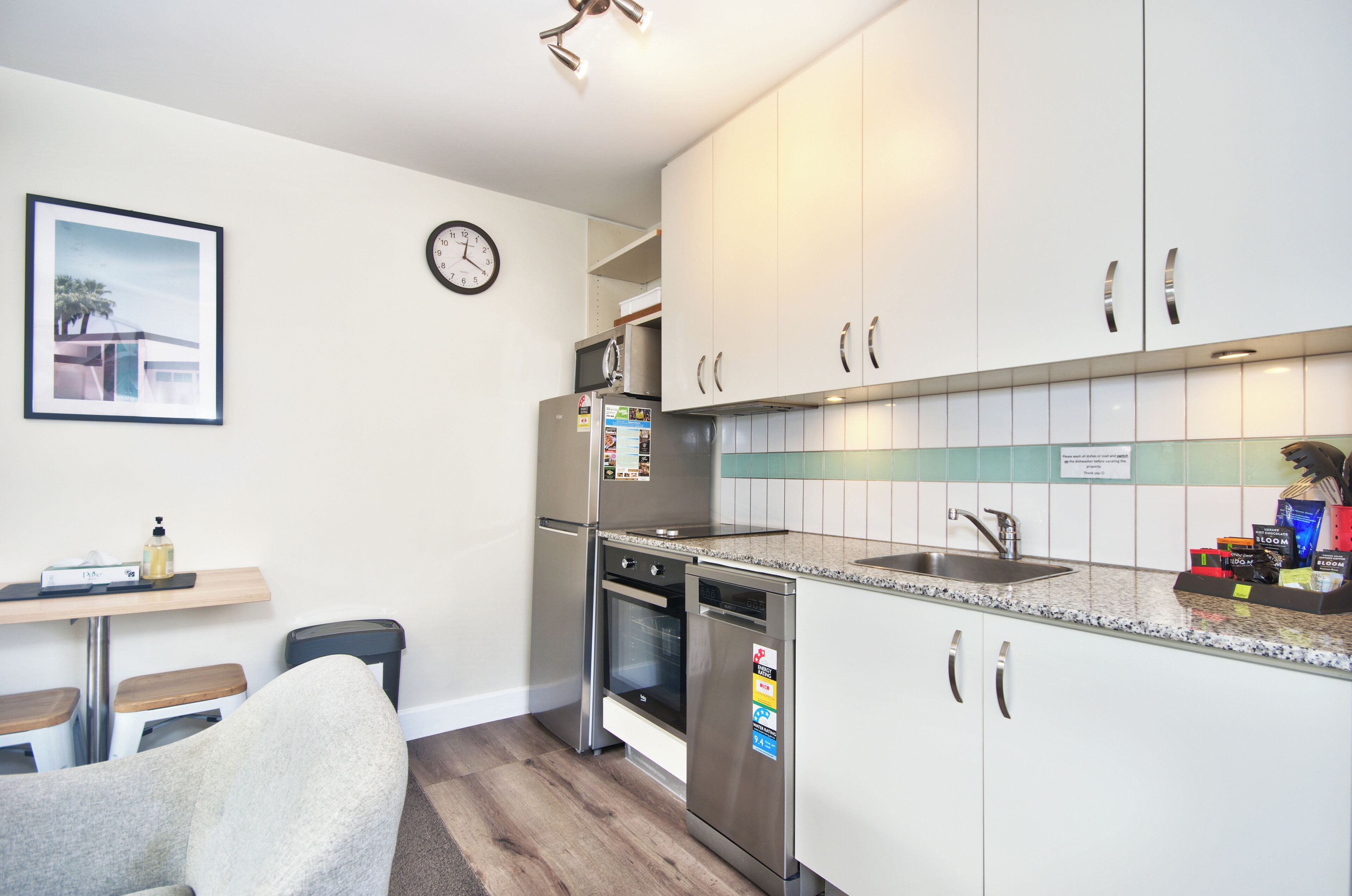 A modern kitchen with white cabinets, stainless steel appliances, a built-in oven, and a sink.
