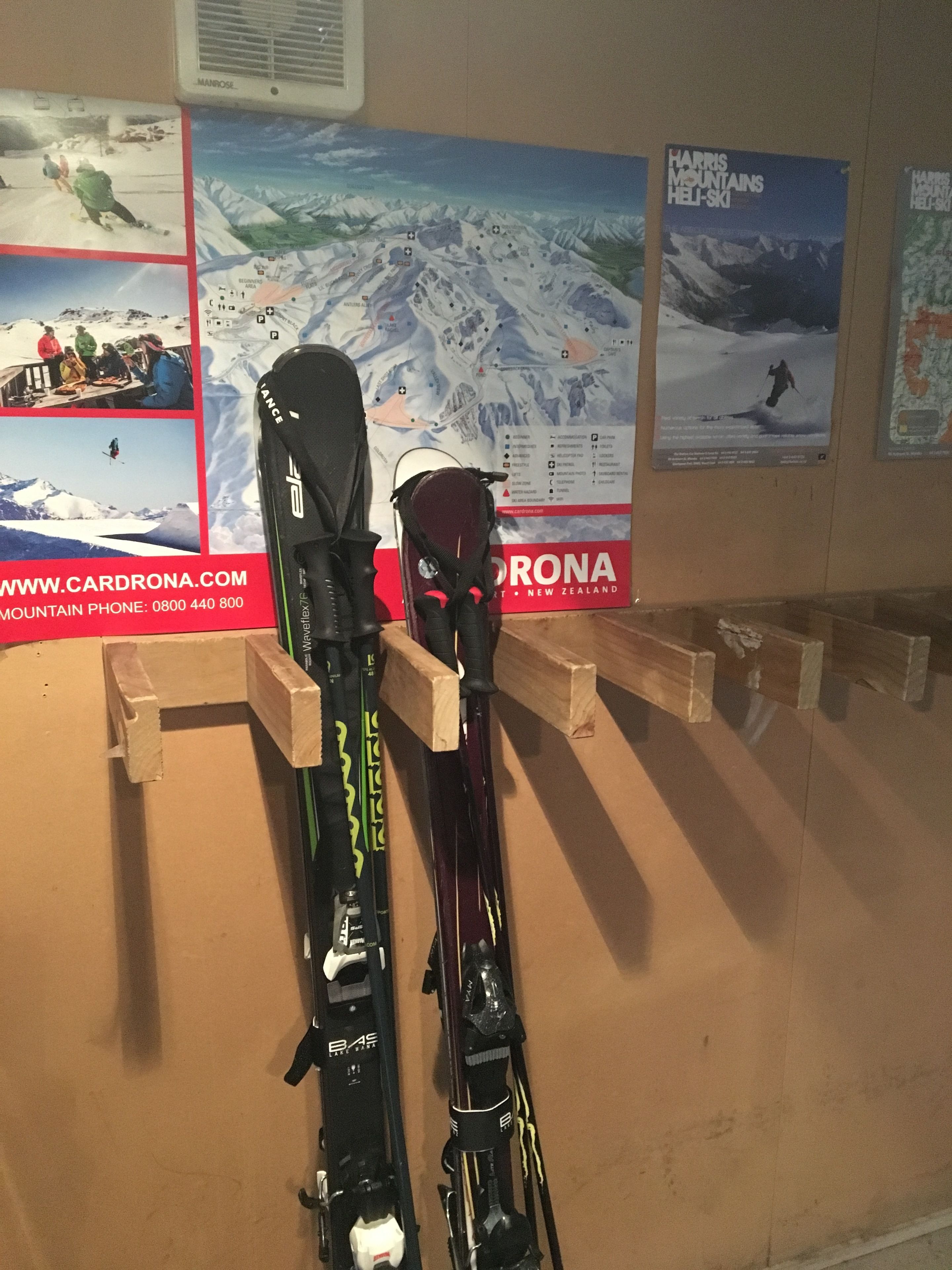 Skis mounted on a wall with a poster of a ski resort in the background.