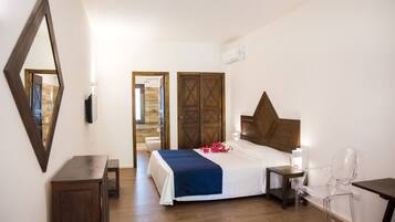 Una habitación de hotel con cama, mesita de noche, silla, armario de madera y espejo.