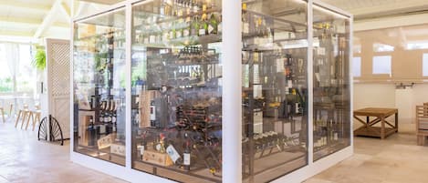 A wine cellar with glass walls, wooden flooring, and hanging wine racks.