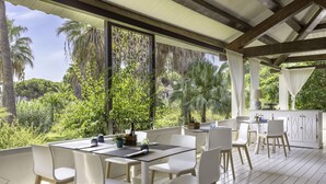 An outdoor patio with white furniture, a dining table, and a kitchen area with a white cabinet. - Hotel Costa Dei Fiori (Pula)